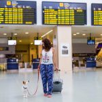 Traveling woman and her dog walking in the airport.